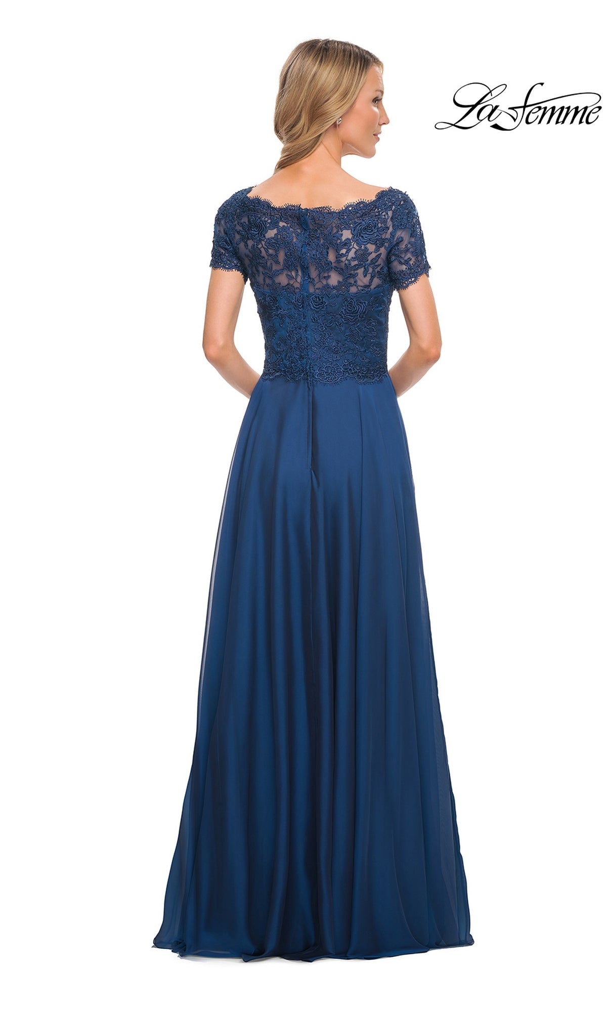 Woman in the Long Formal Dress: La Femme 27098, featuring a lace embroidered bodice and chiffon A-line skirt, stands with her back to the camera in a navy blue gown.